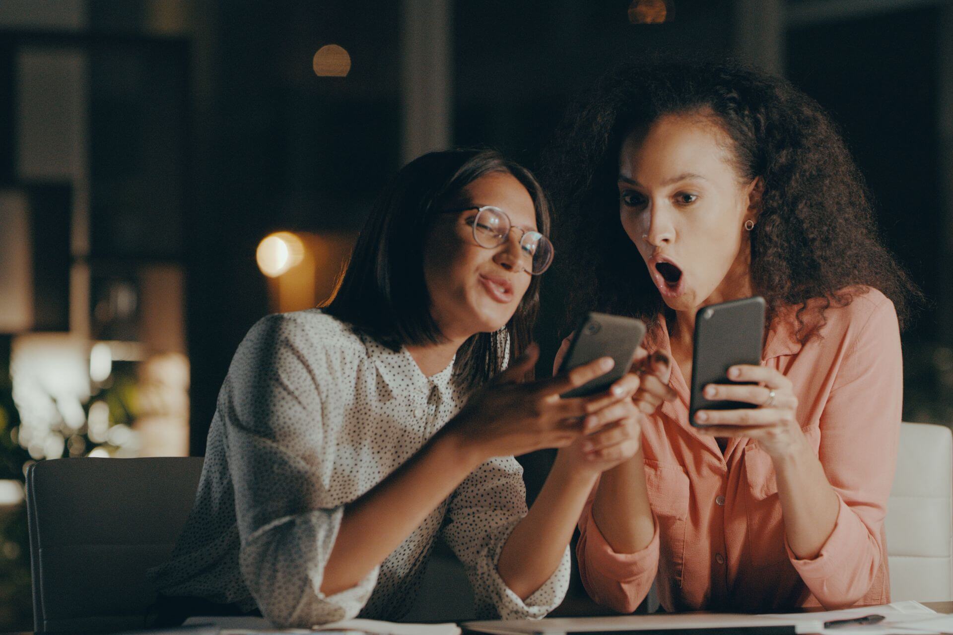 Two woman comparing Online MBA vs. In-Person MBAs on thier phones.